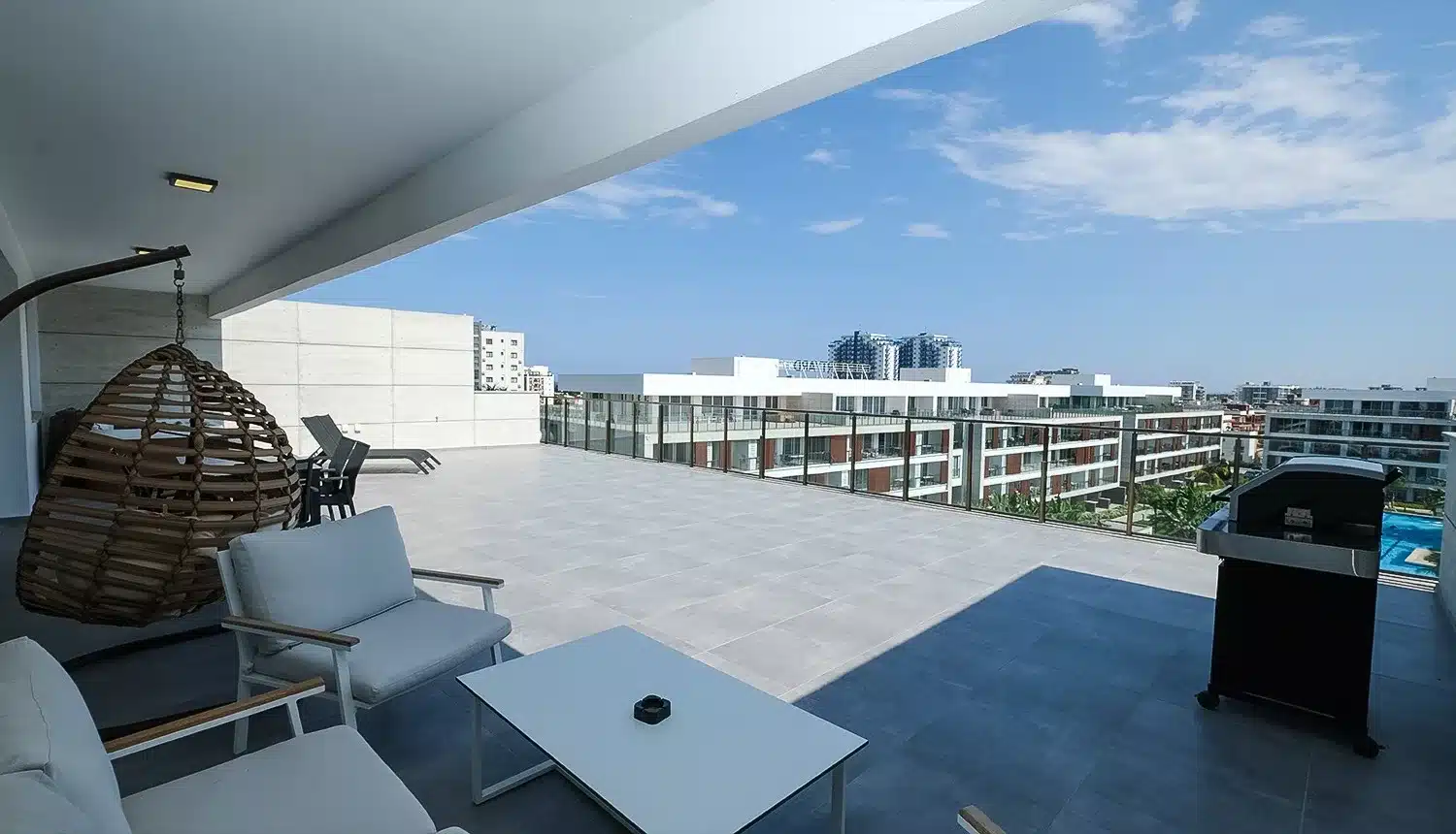 Überdachte Terrasse im Courtyard mit Hängesessel und Blick über die Wohnanlage