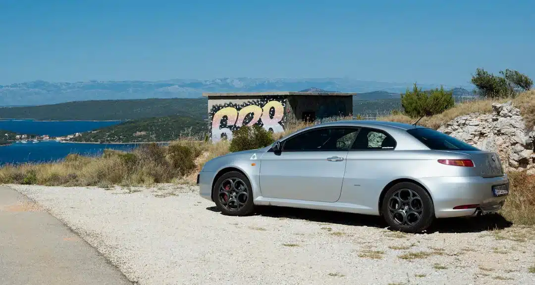 Silbernes Auto mit Blick auf das Meer als Symbol für Fahrzeugkauf oder Mietwagen